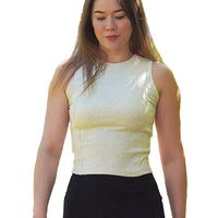 Woman wearing a light-colored sleeveless top and black skirt outdoors with greenery in the background