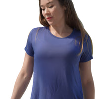 Woman wearing a blue t-shirt outdoors with greenery in the background