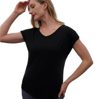 Woman wearing a black top and purple leggings against a dark background