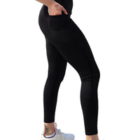 Person wearing black leggings and white sneakers in an outdoor setting with rocks and greenery.
