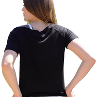 Person wearing a black t-shirt and white pants standing outdoors with trees in the background