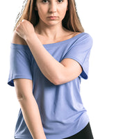 Woman wearing a blue off-shoulder top and black shorts outdoors.