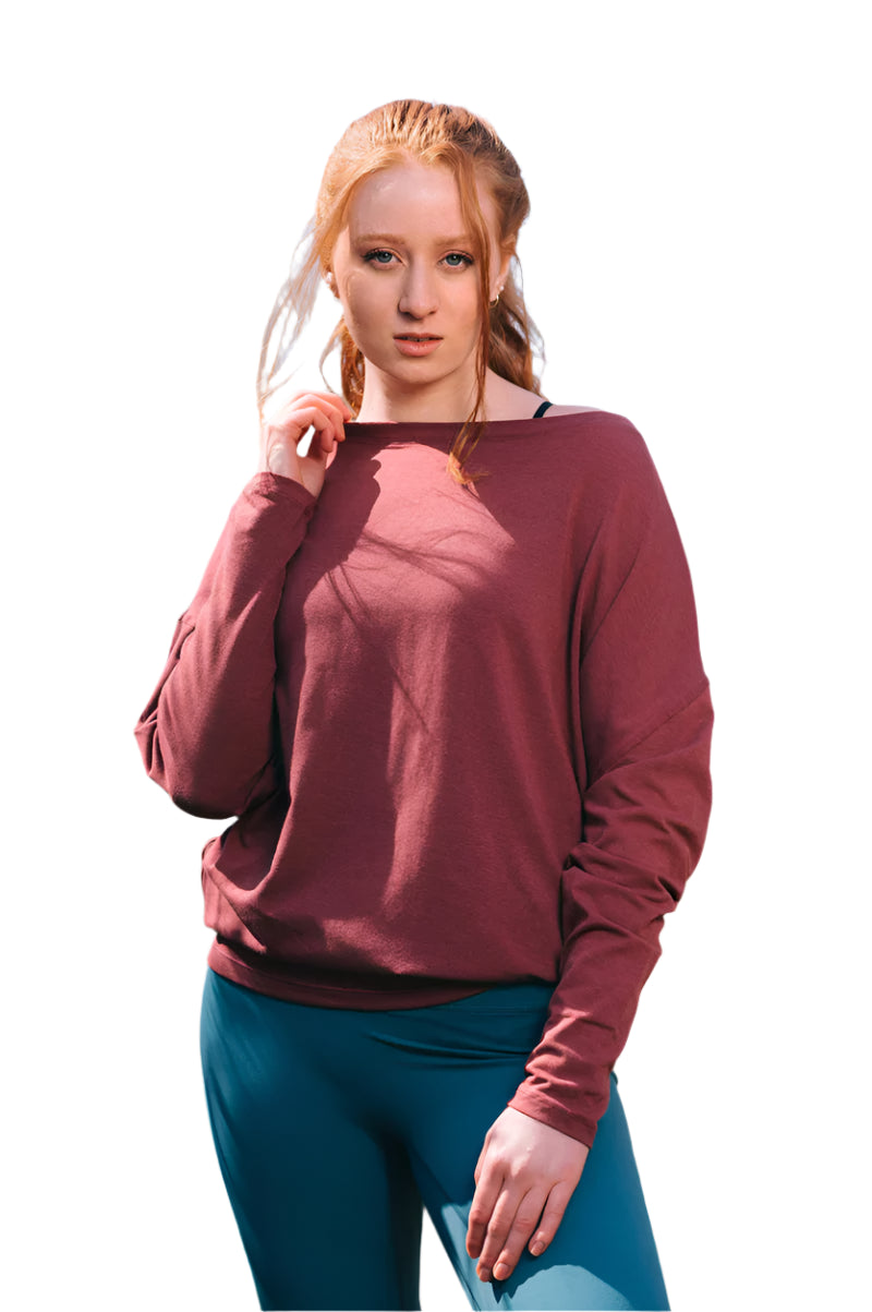 Woman wearing a maroon long-sleeve top and blue leggings outdoors.