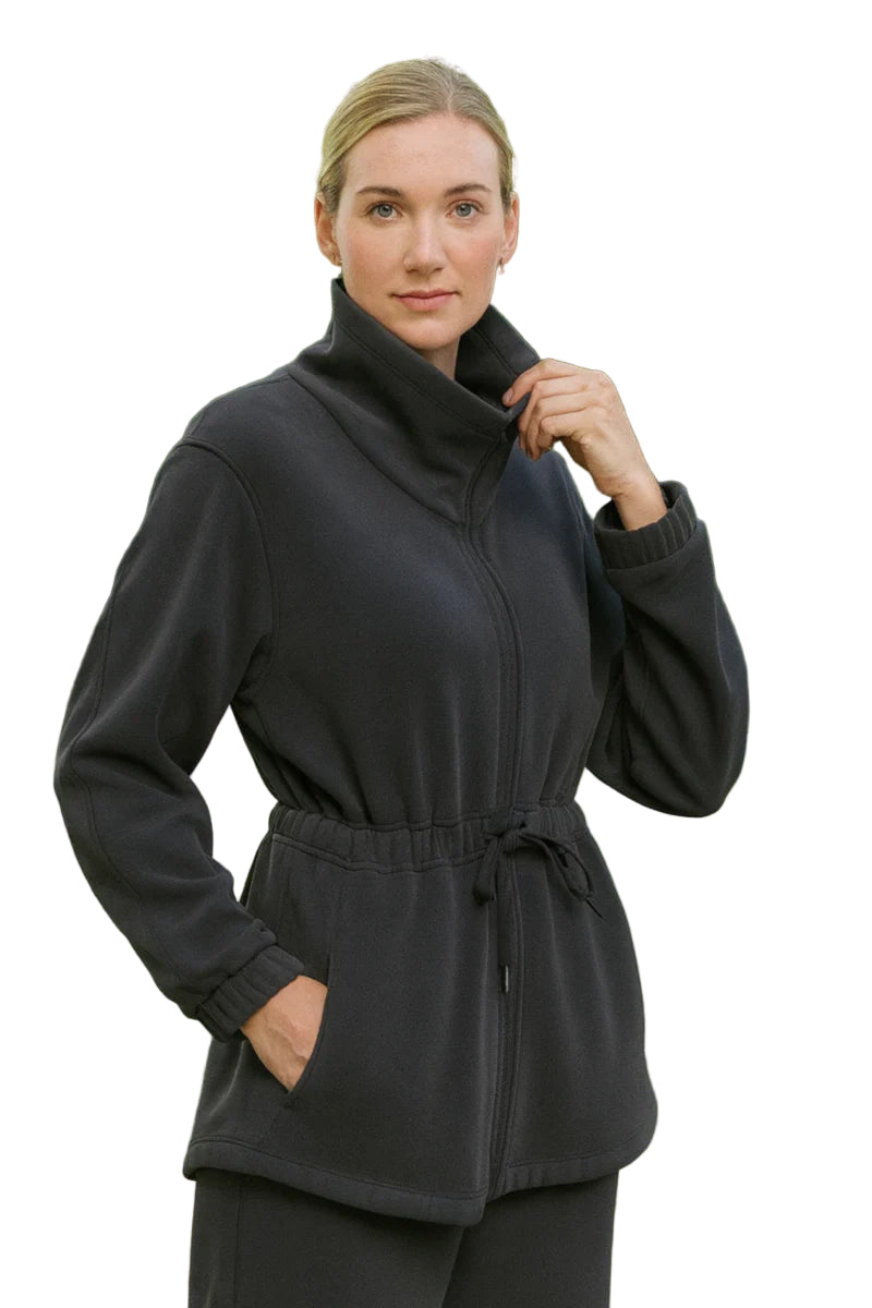 Woman wearing a black jacket with a cowl neck and belt in an outdoor setting.