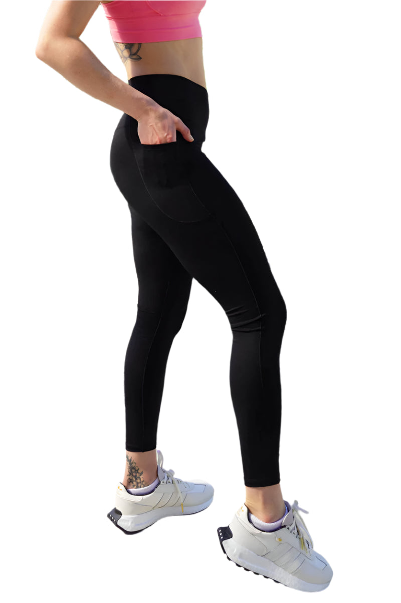 Person wearing black leggings and white sneakers in an outdoor setting with rocks and greenery.