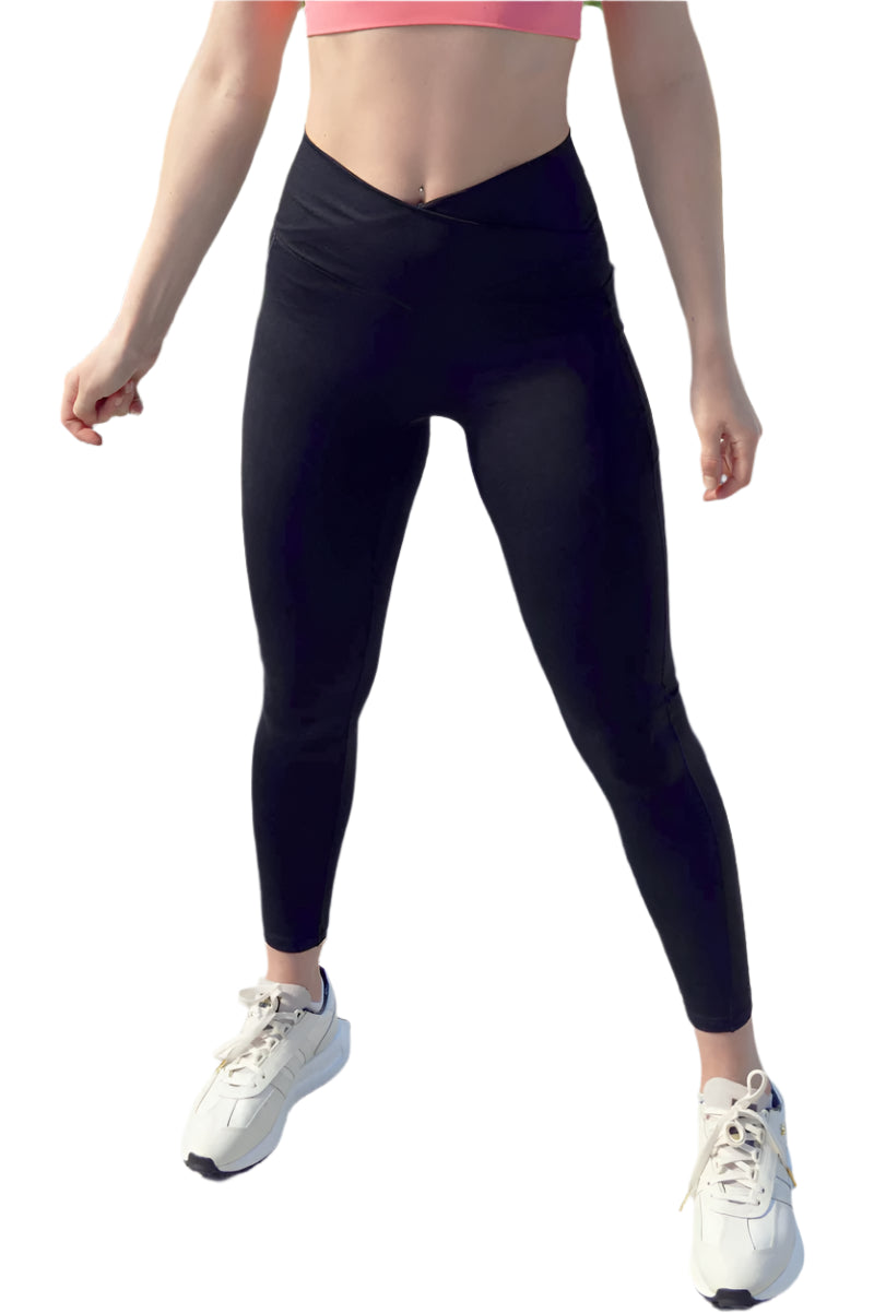 Person wearing black leggings and white sneakers standing on a stone surface with a natural background.