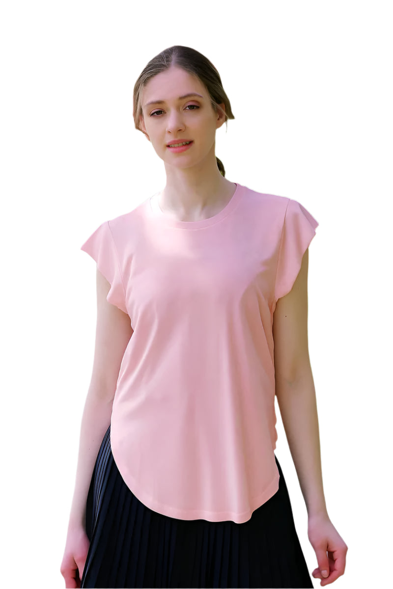 Woman wearing a pink top and black skirt standing in a park with cherry blossom trees.