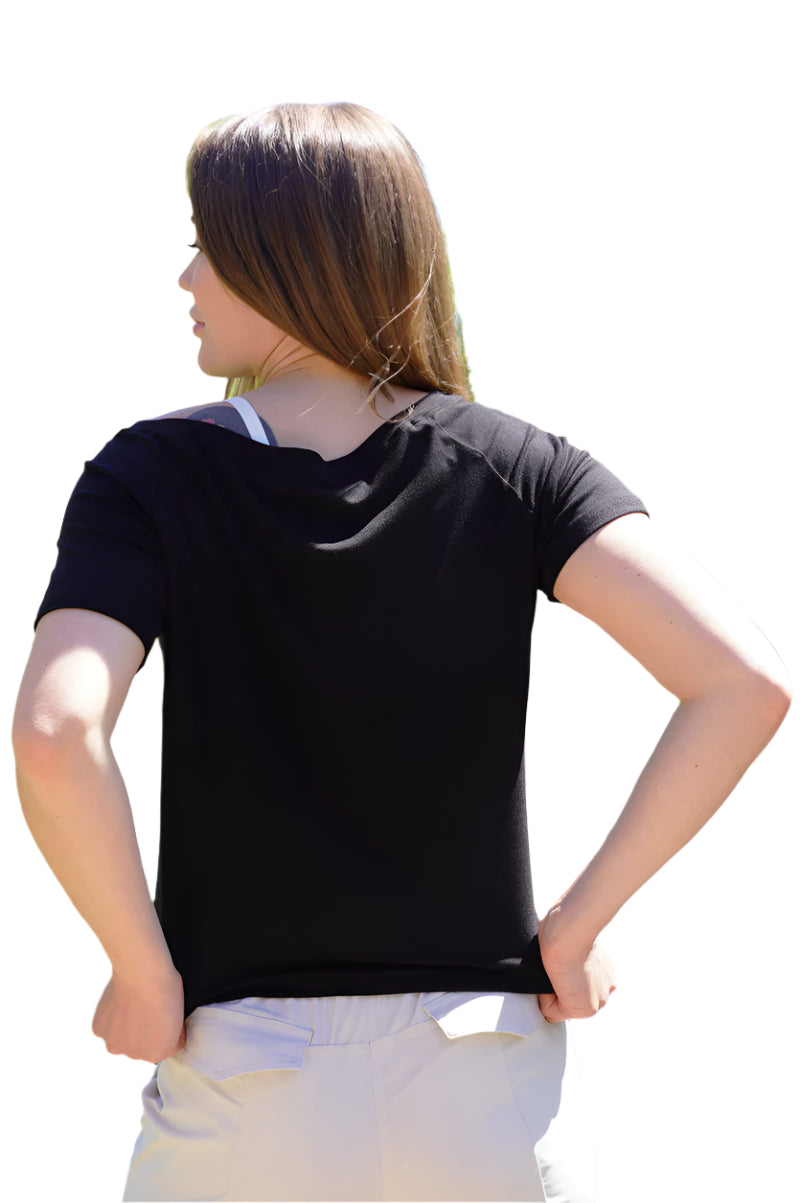 Person wearing a black t-shirt and white pants standing outdoors with trees in the background
