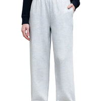 Person wearing light gray sweatpants and white sneakers on a city street.