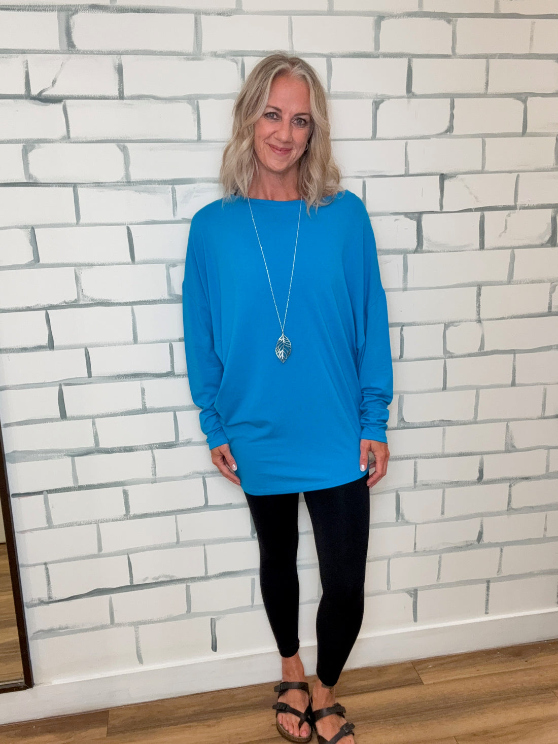 Person wearing a blue hoodie and black pants standing on a tiled floor.