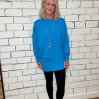 Person wearing a blue hoodie and black pants standing on a tiled floor.